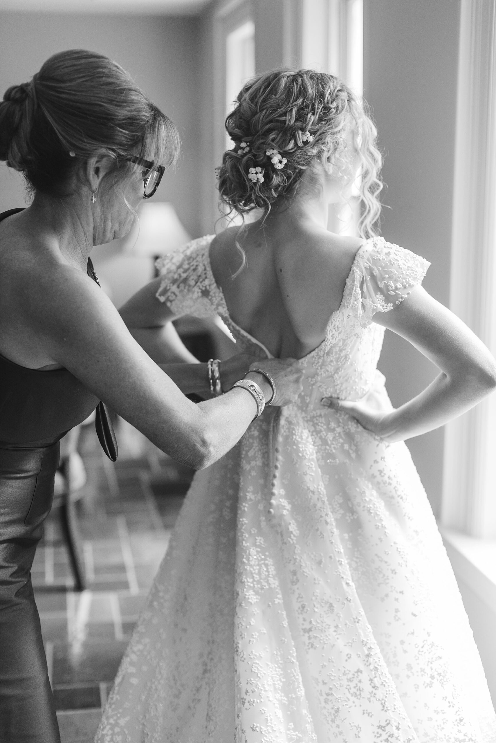 mom helps bride into wedding dress