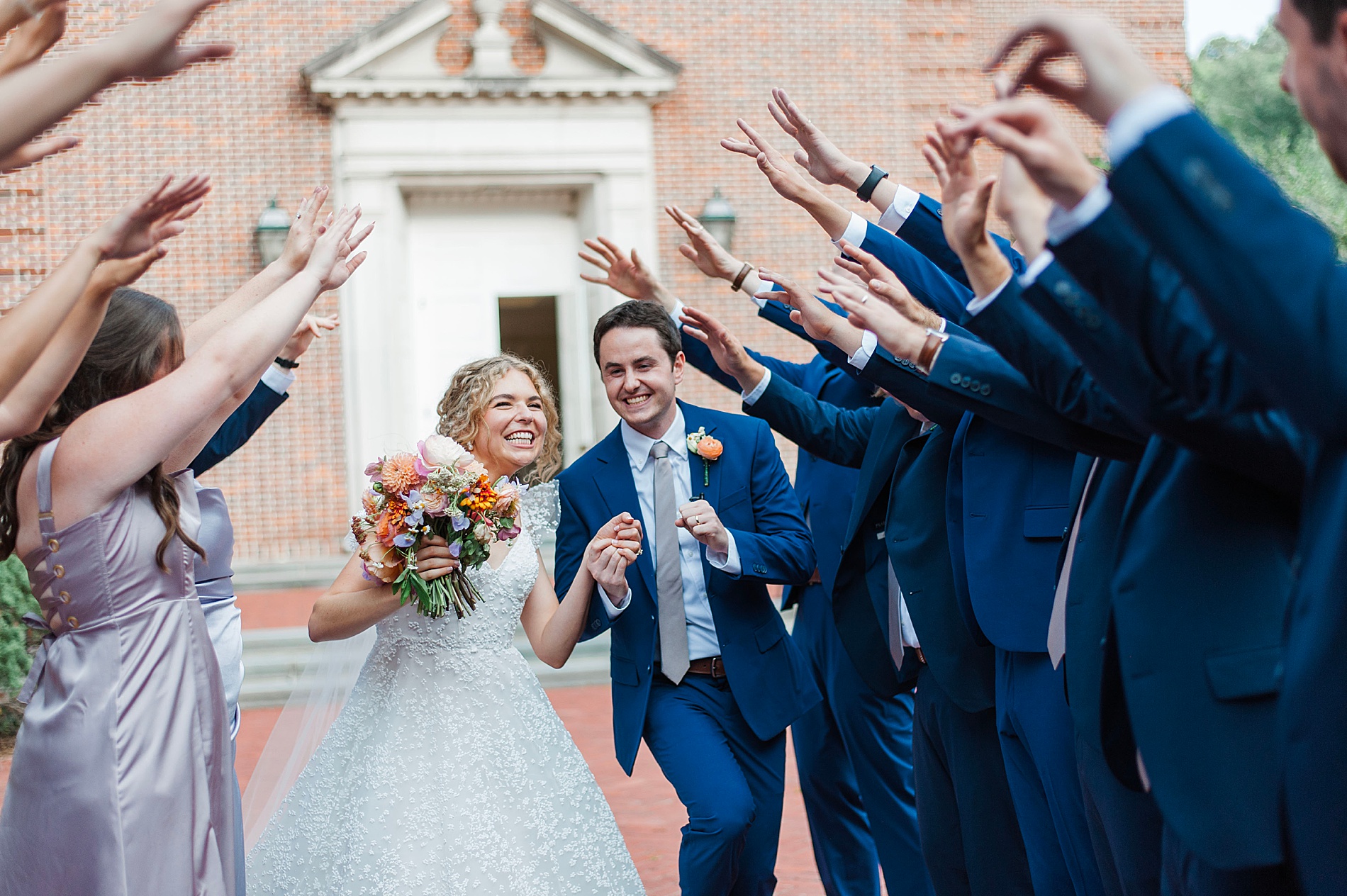 newlyweds walk through tunnel by bridal party