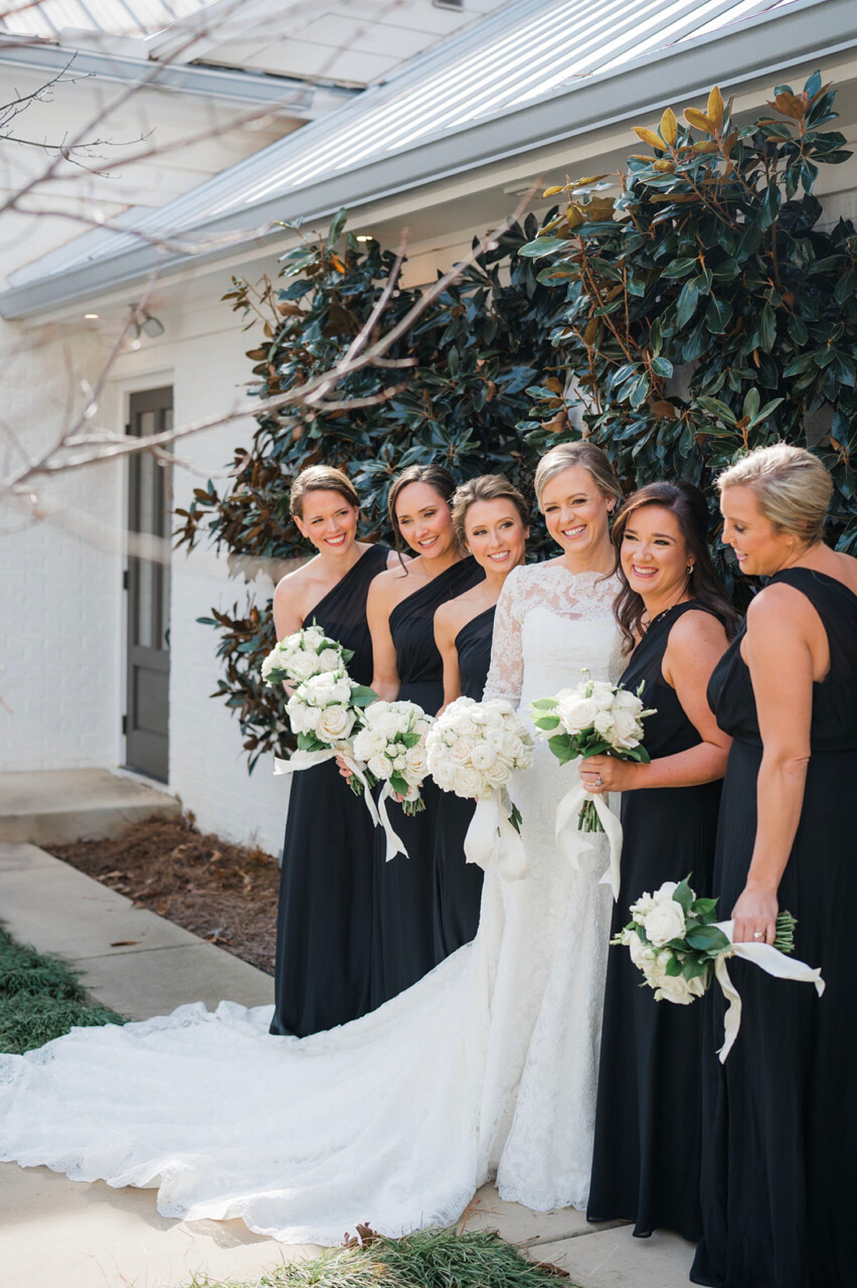 bride with bridal party in black dresses and white bouquets