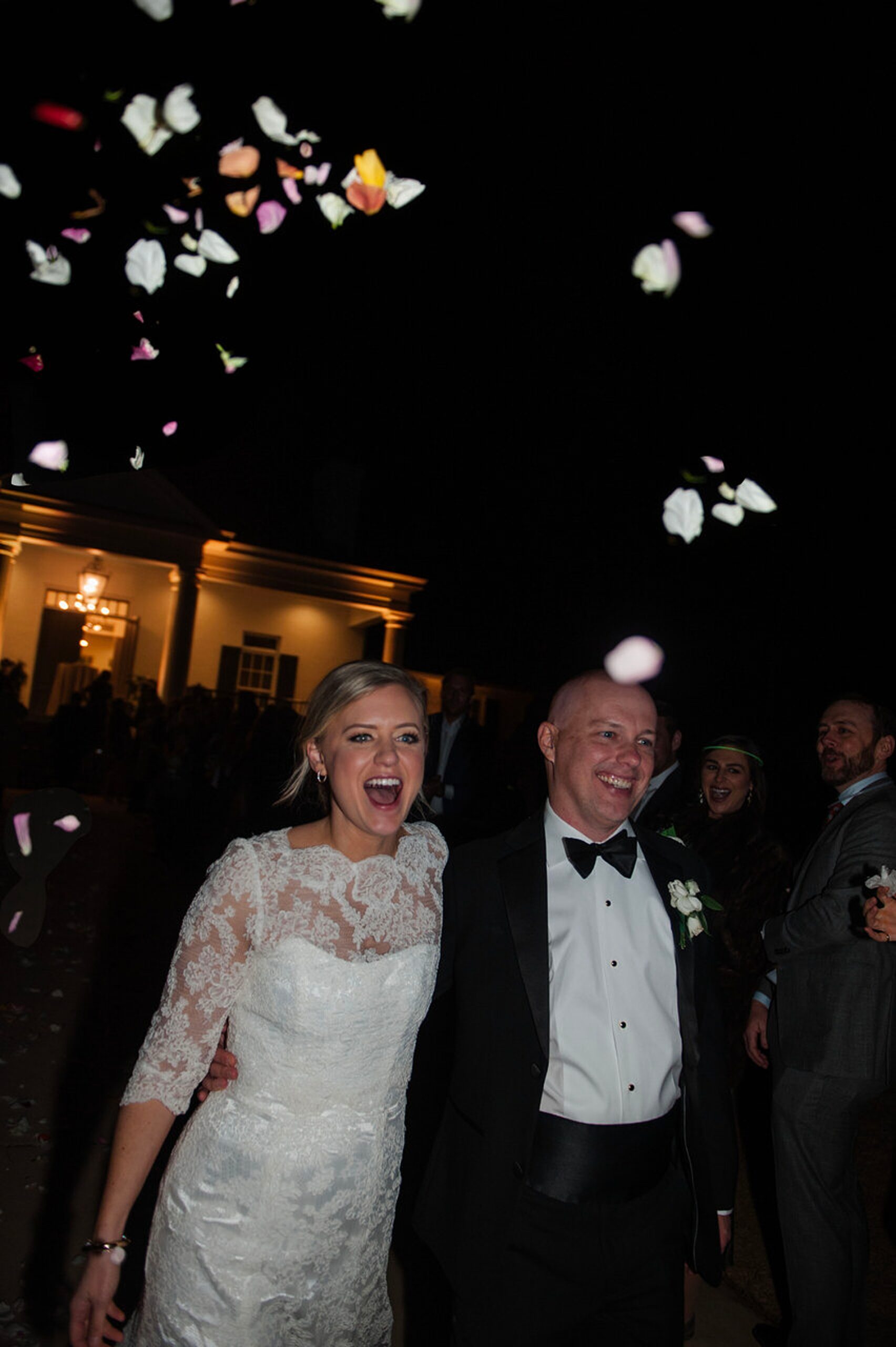 guests throw flower petals as newlyweds exit wedding 