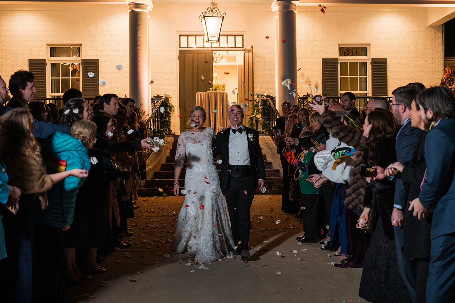 newlyweds exit wedding reception as guests throw flower petals