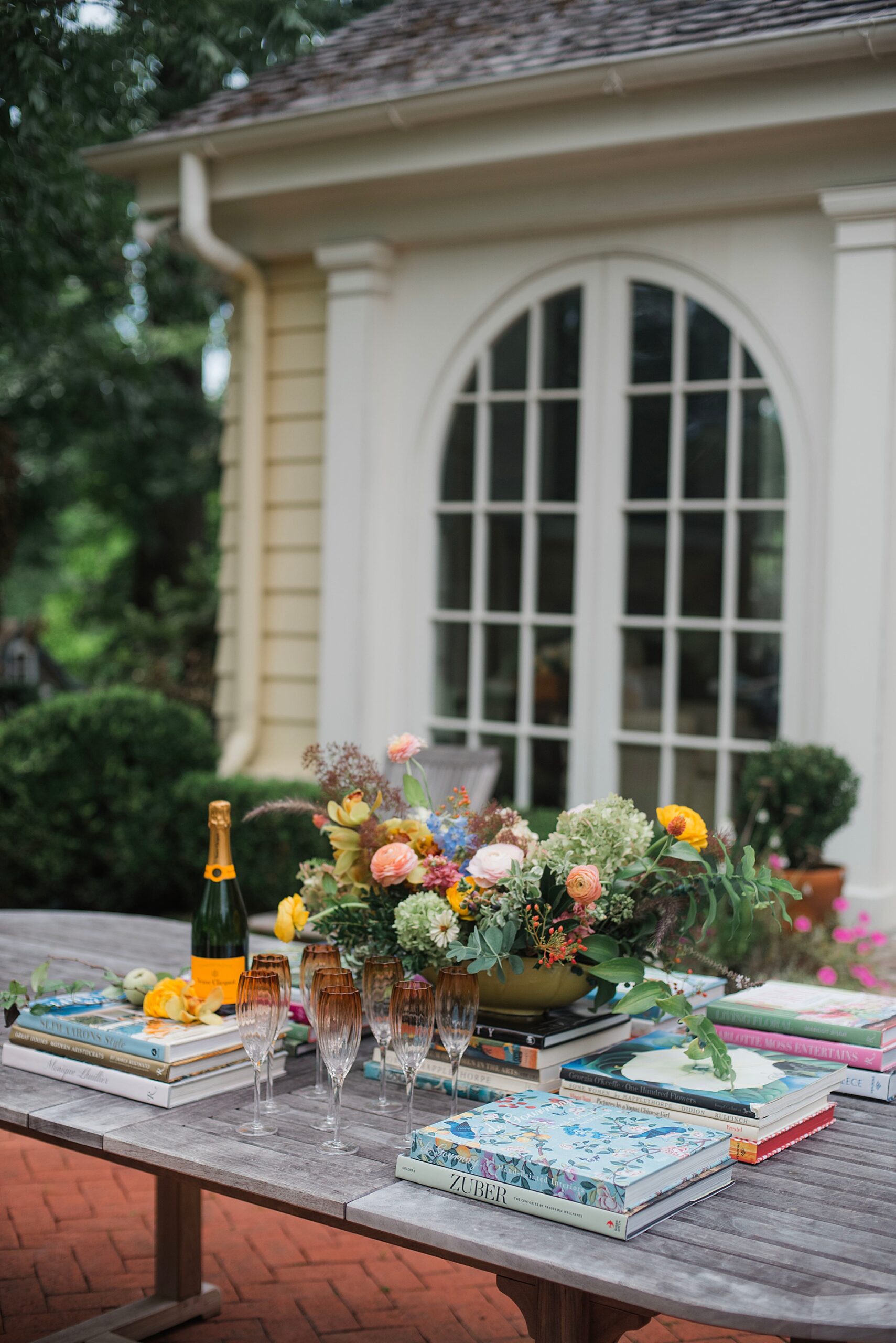 champagne on table with glassware and wedding books for outdoor brunch celebrating bride-to-be.