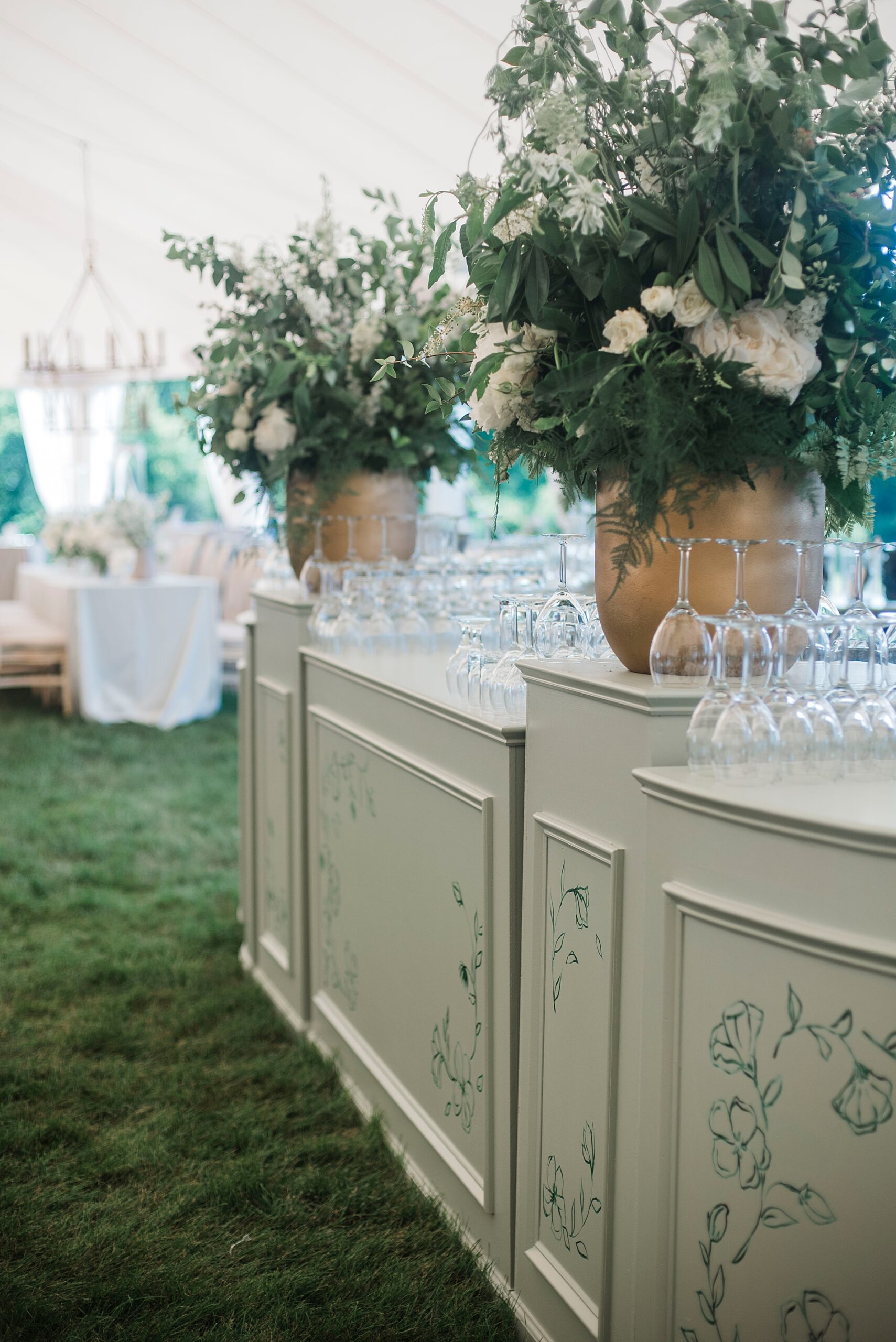 sage green bar with classic floral arrangements with ample greenery and white blooms