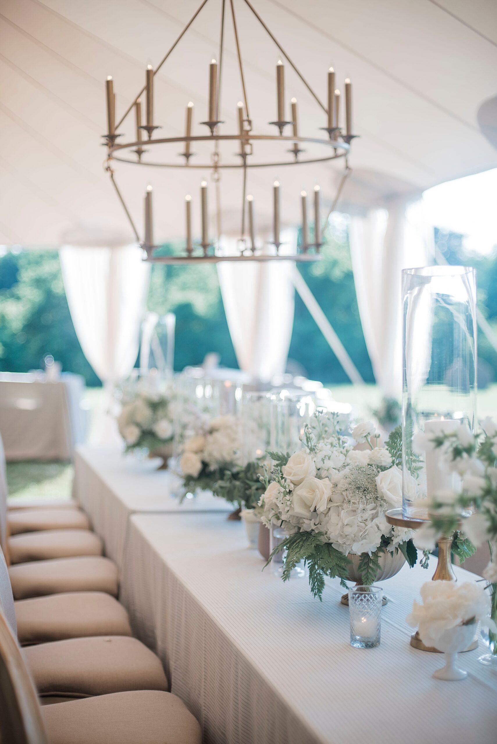 Classic white flower centerpieces decorate formal dinner table at reception