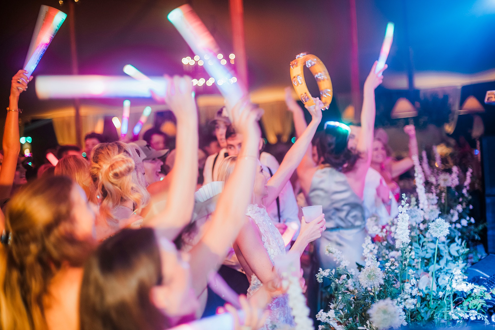 bride and groom and wedding guests with glow sticks out on dance floor