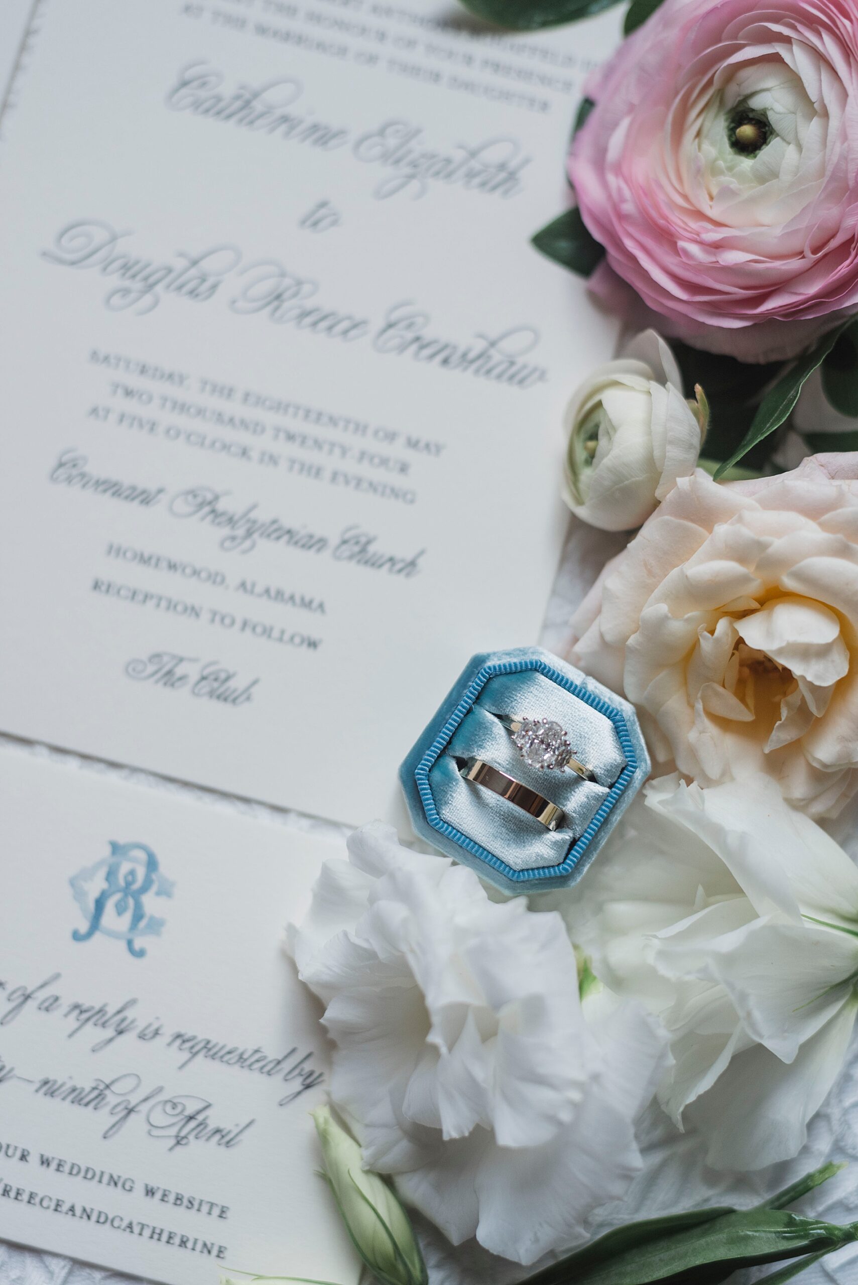 rings in blue ring box next to invitation