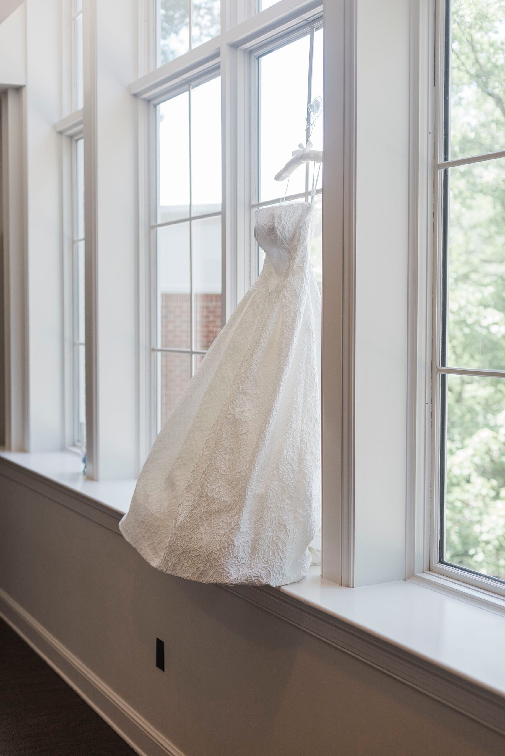 wedding dress hangs by window