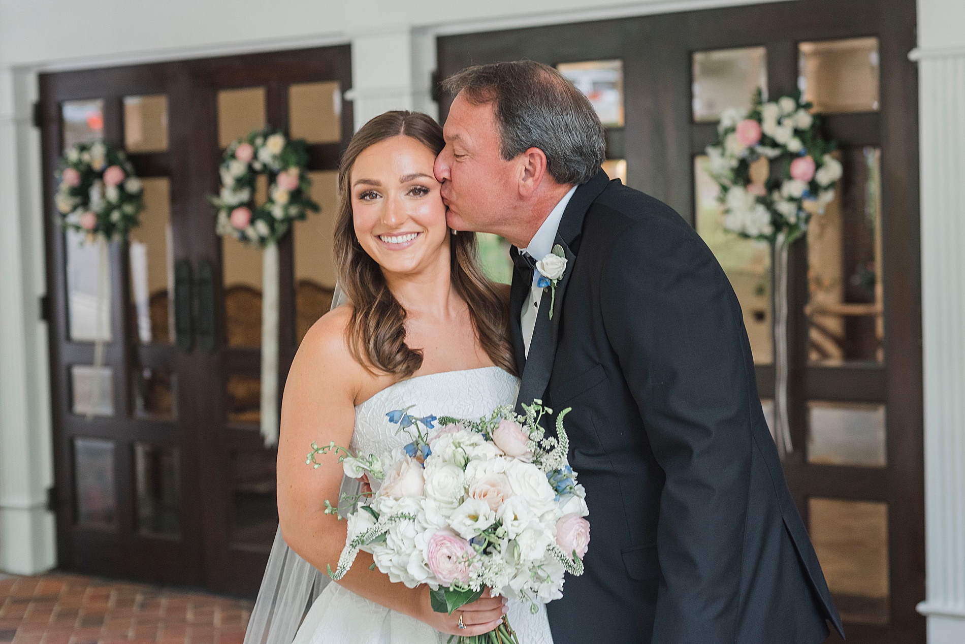 father of the bride kisses bride's cheek