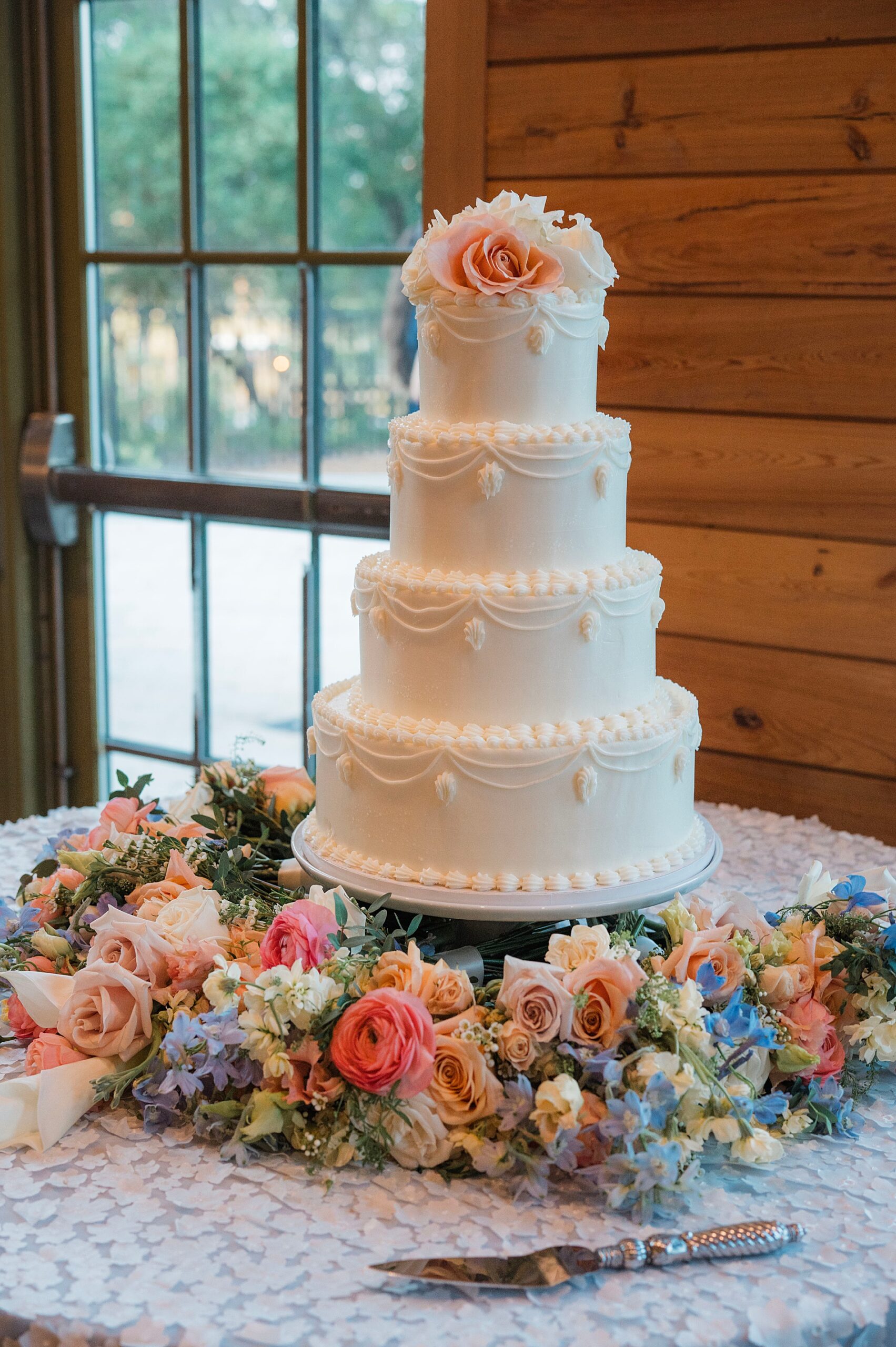 4 tiered wedding cake surrounded by florals