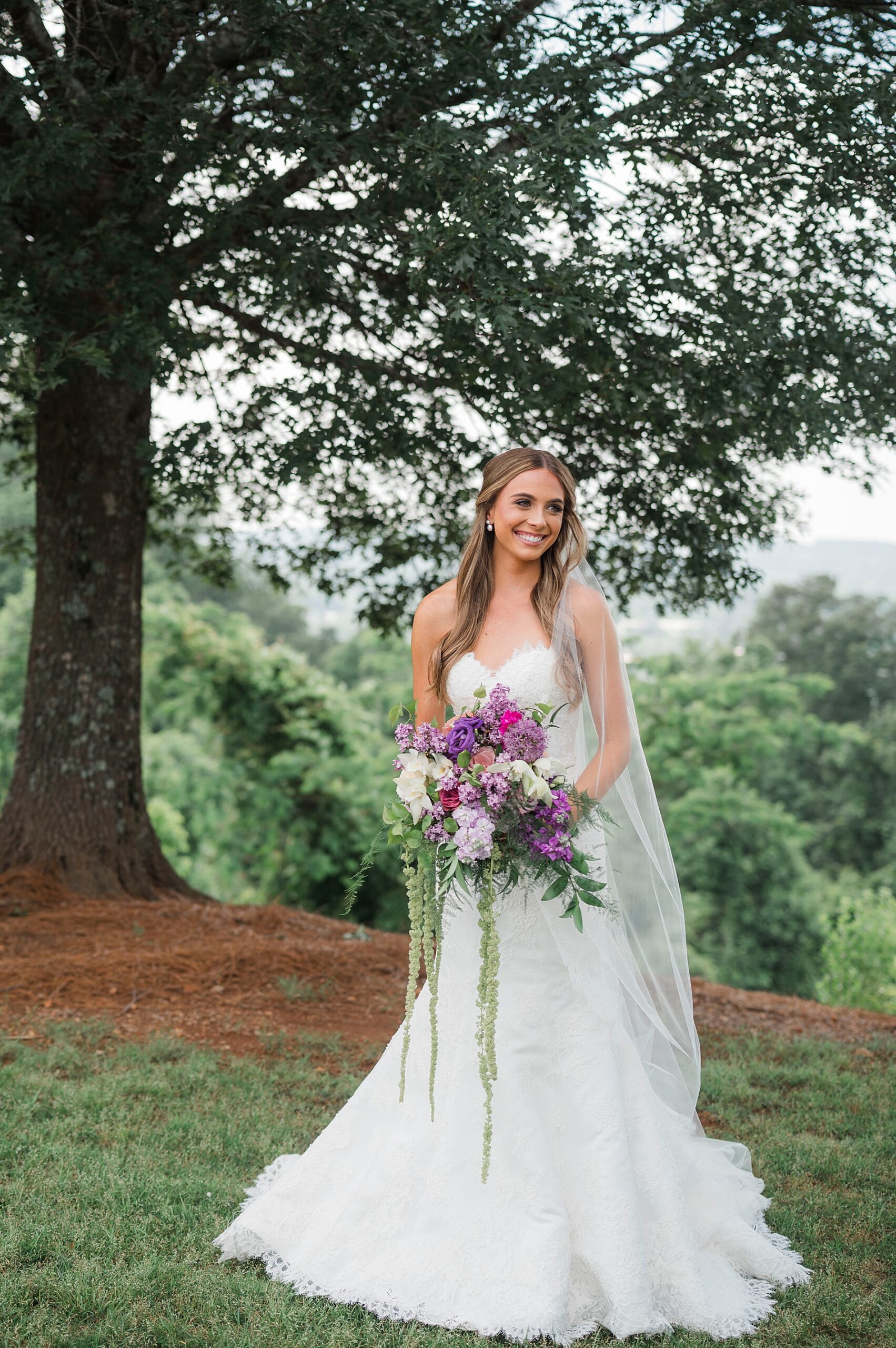 bride holds bouquet of white and purple flowers