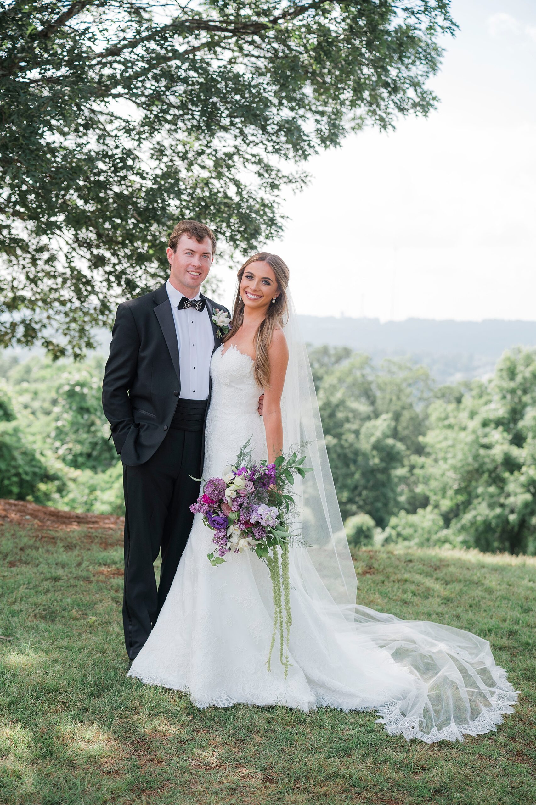 bride and groom portraits on hill overlooking land below