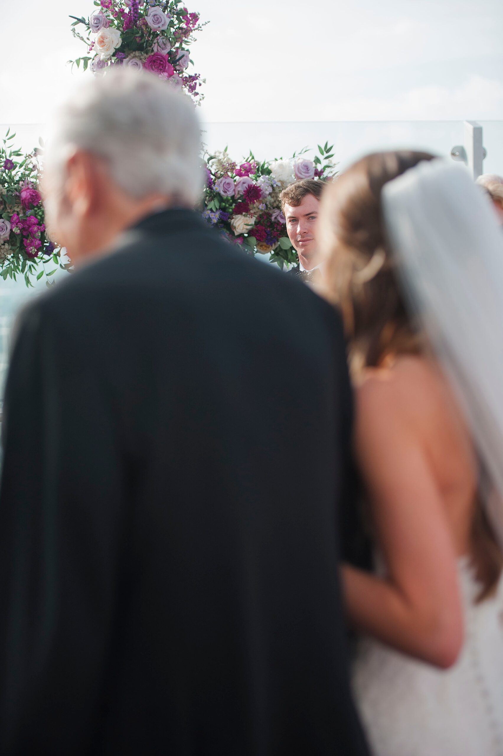 groom watches bride walk down the aisle with father