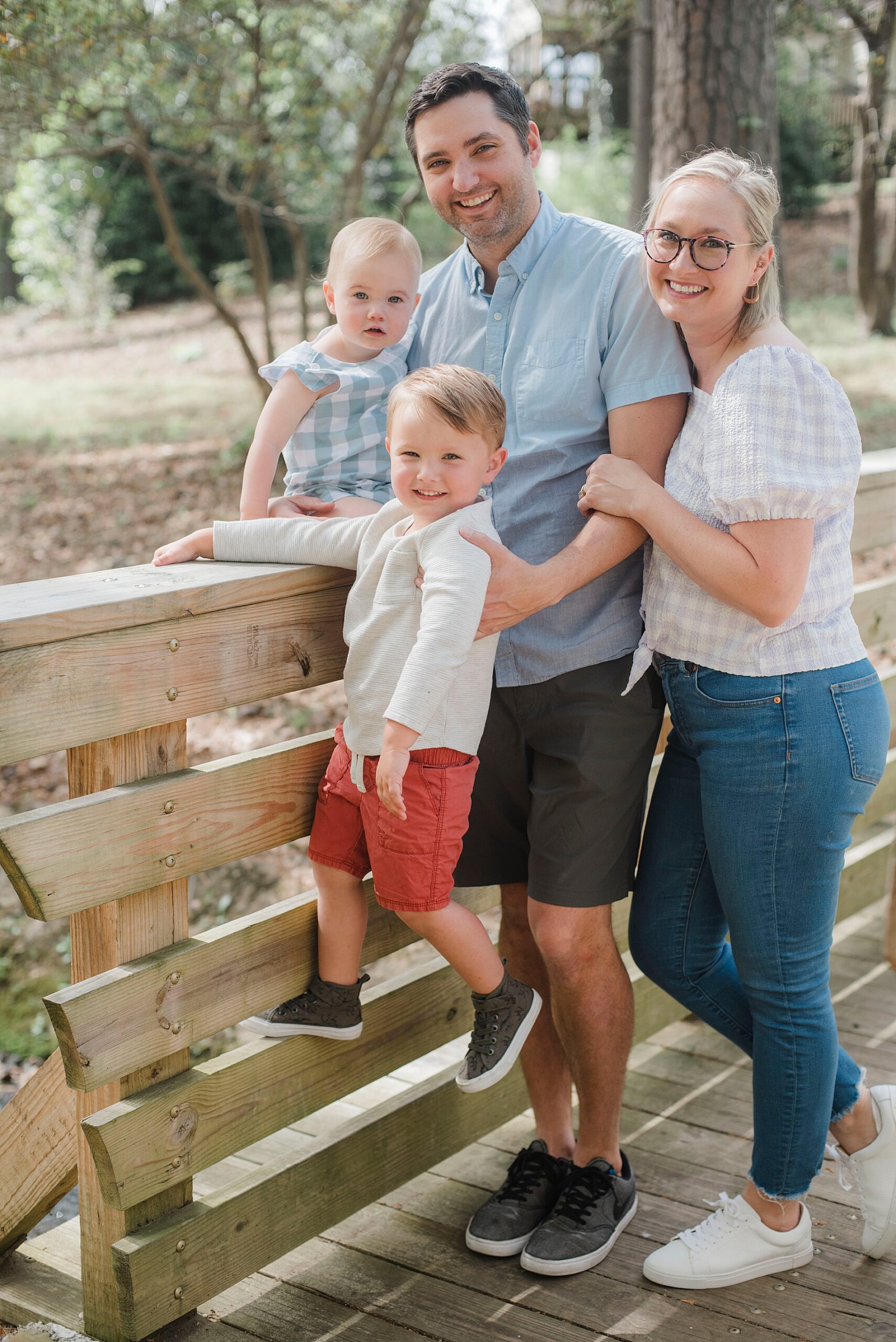family of four by wooden fence