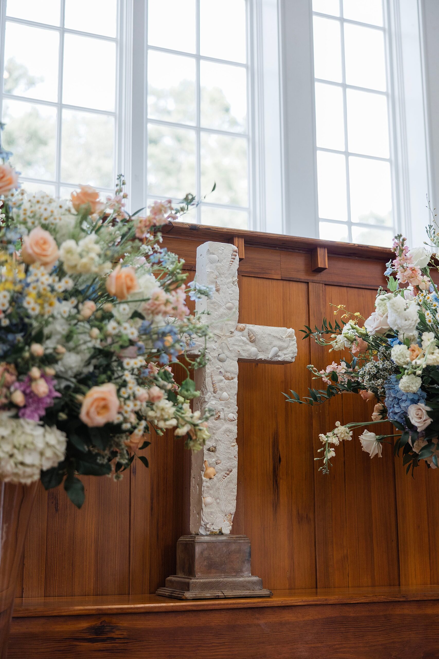 soft florals around white cross at chapel