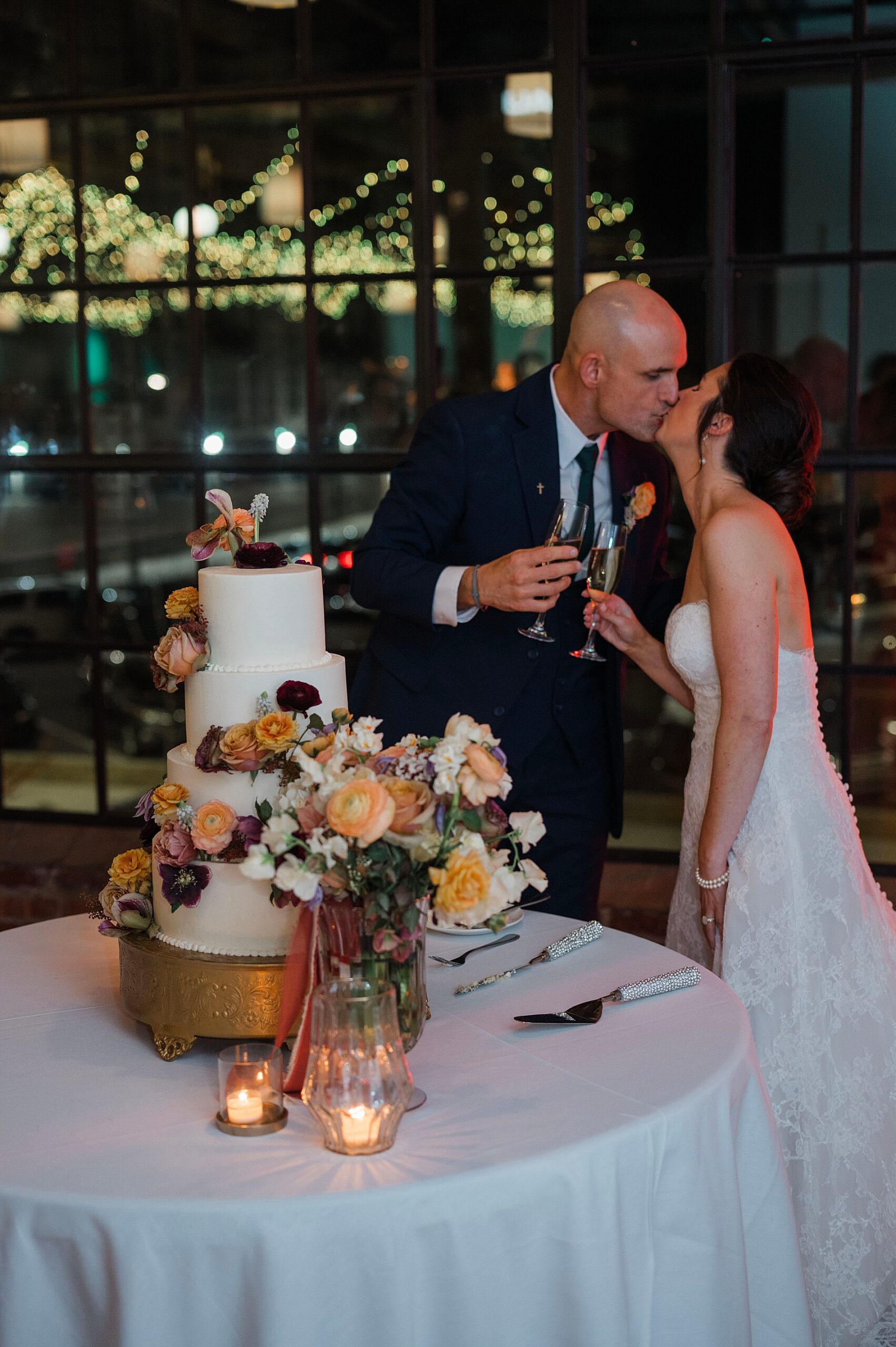bride and groom kiss by wedding cake table
