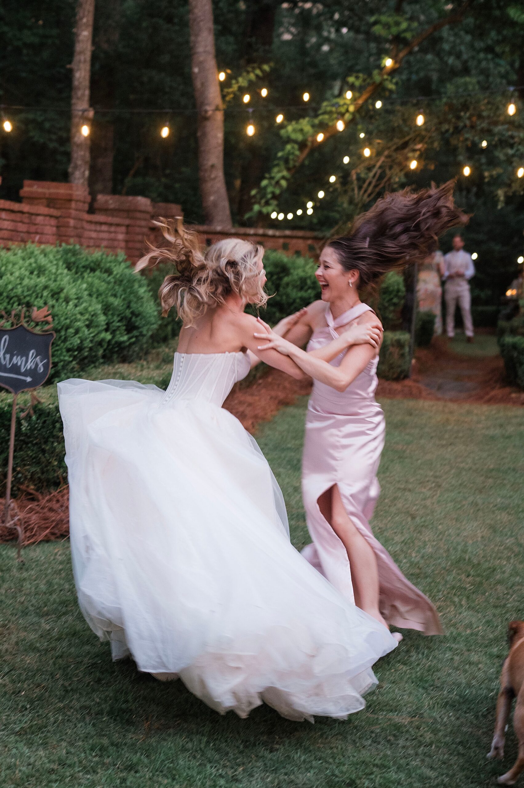 bride jumps up and down with bridesmaid. 