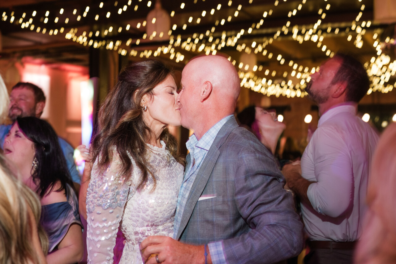 newlyweds kiss on dance floor under stringed lights