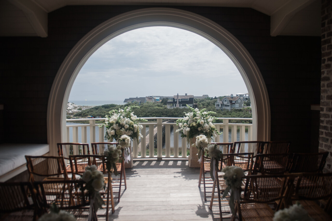 wedding ceremony on balcony of beach house overlooking the water 