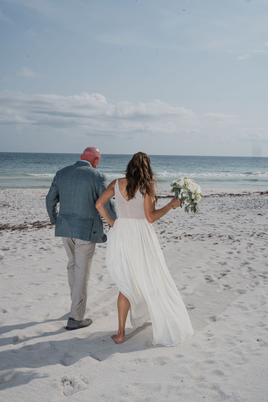 couple hold hands as they walk in the sand of 30A beach
