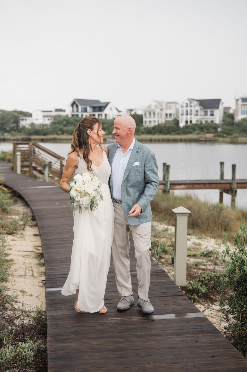 bride and groom walk along the boardwalk of water in 30A 