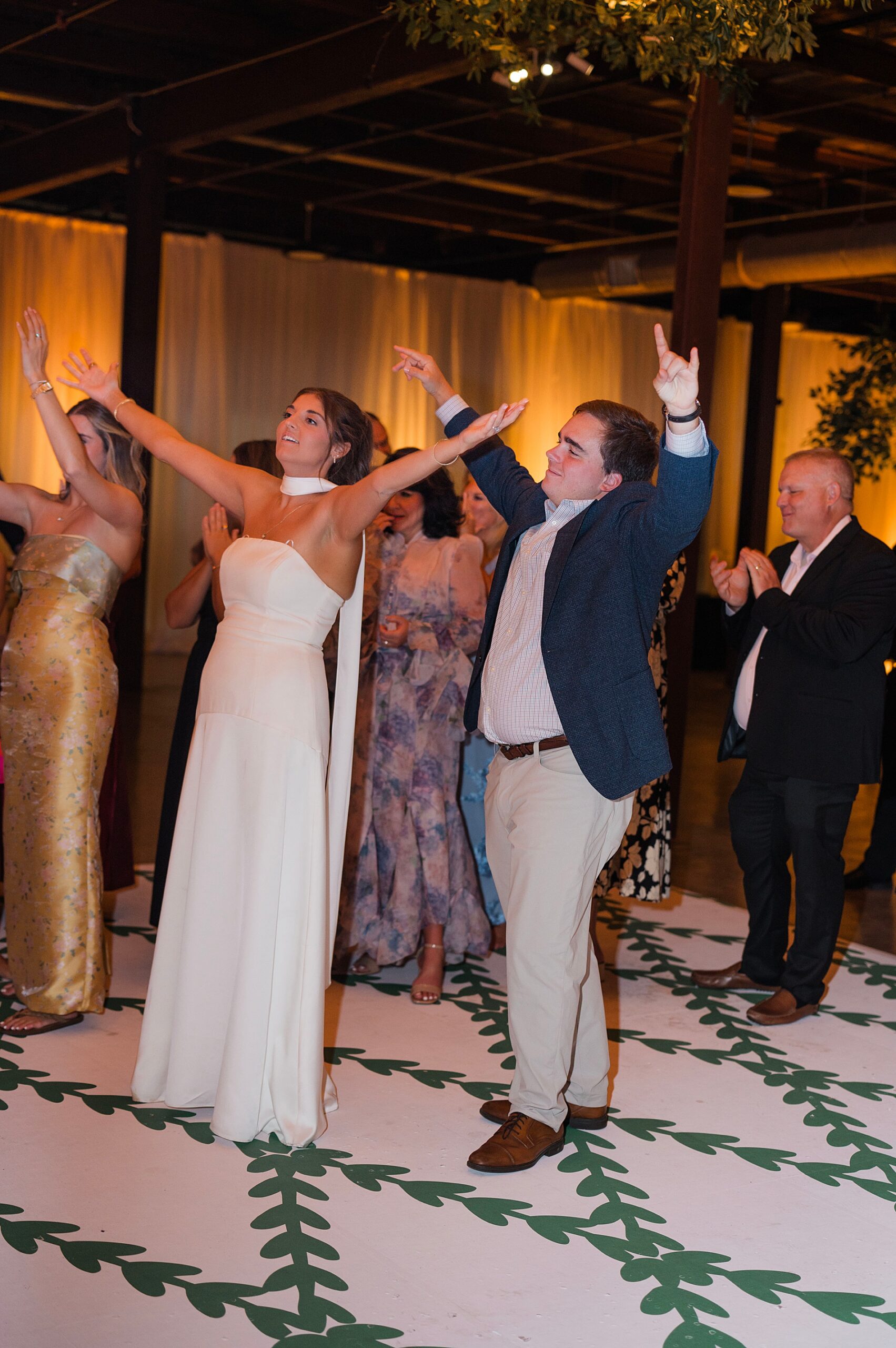 bride and groom dancing with their arms in the air 